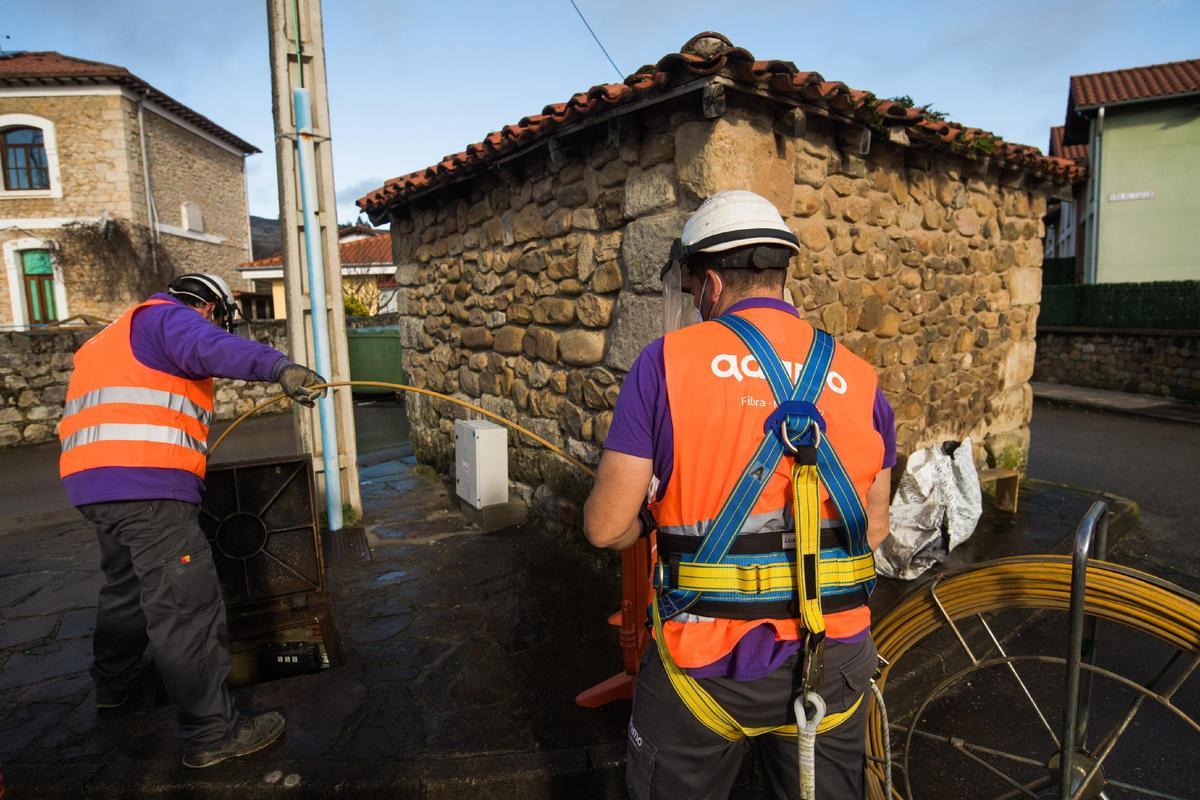Dos operarios trabajan en un pueblo para instalar la fibra óptica.