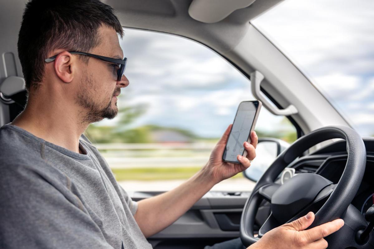 Un conductor consulta el móvil mientras conduce
