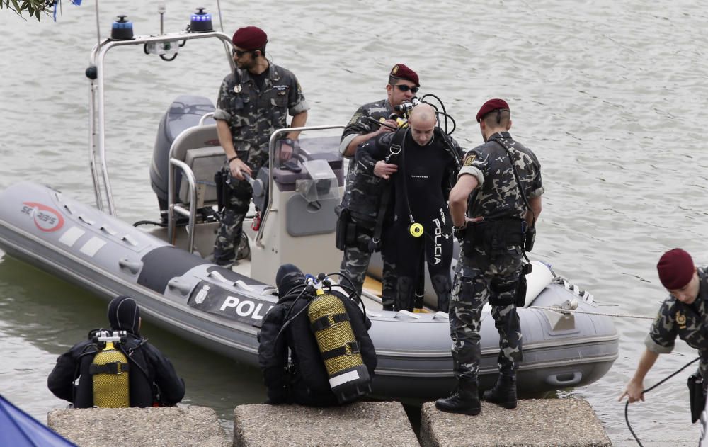 Los especialistas, que necesitan luz natural, trabajan en una zona balizada en un margen del río, apoyados por una lancha de la Policía Nacional, todo ello vigilado por agentes que impiden el acceso a la orilla de la dársena.