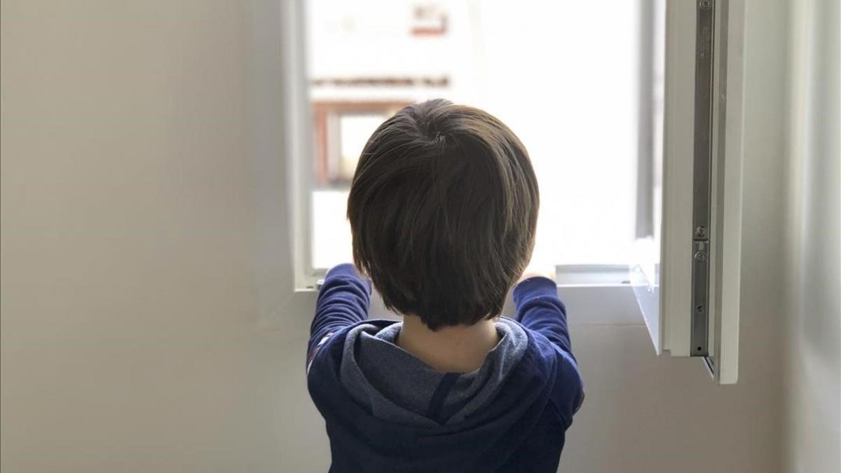 Un niño de cinco años mira por la ventana de su casa, en Madrid