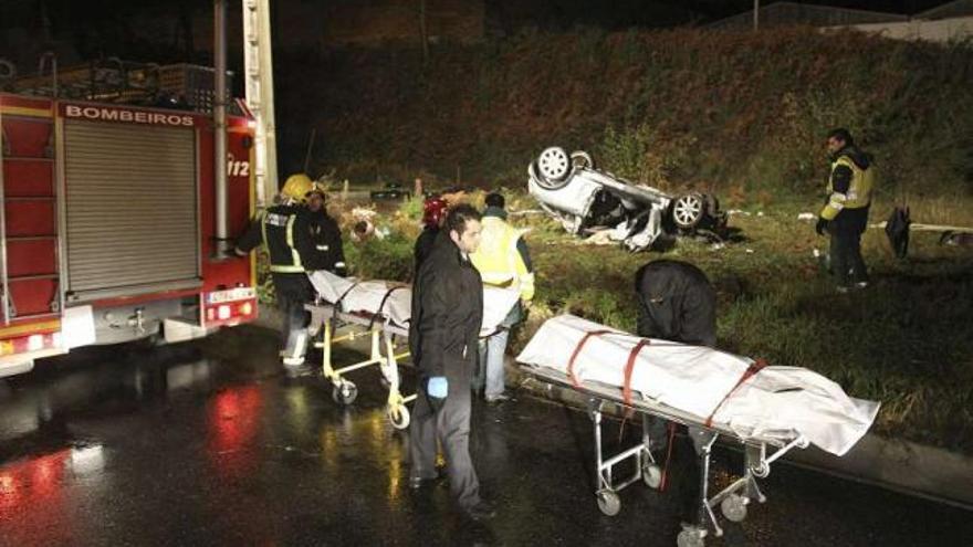 Los bomberos junto a los dos cadáveres, con el coche accidentado al fondo. / sxenick