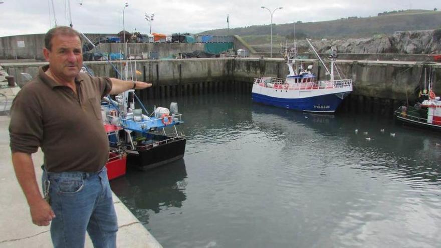 Ángel Batalla señalando la zona de la dársena del puerto de Llanes que no está siendo limpiada, ayer.