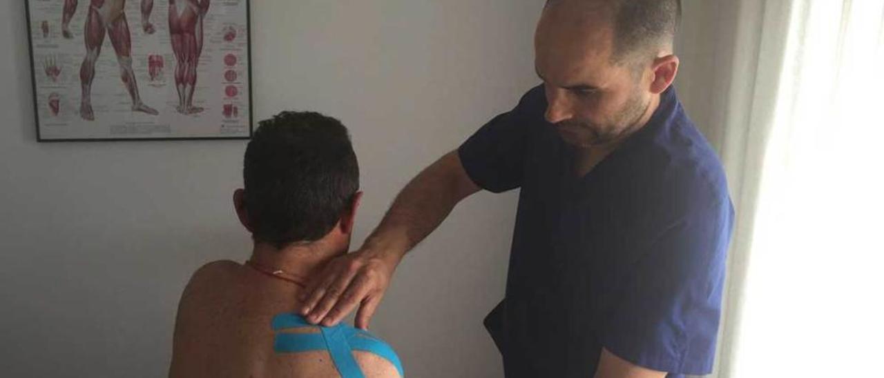 Pedro Montes coloca un vendaje de la técnica &quot;kinesiotape&quot; a un paciente en su clínica de Arriondas.