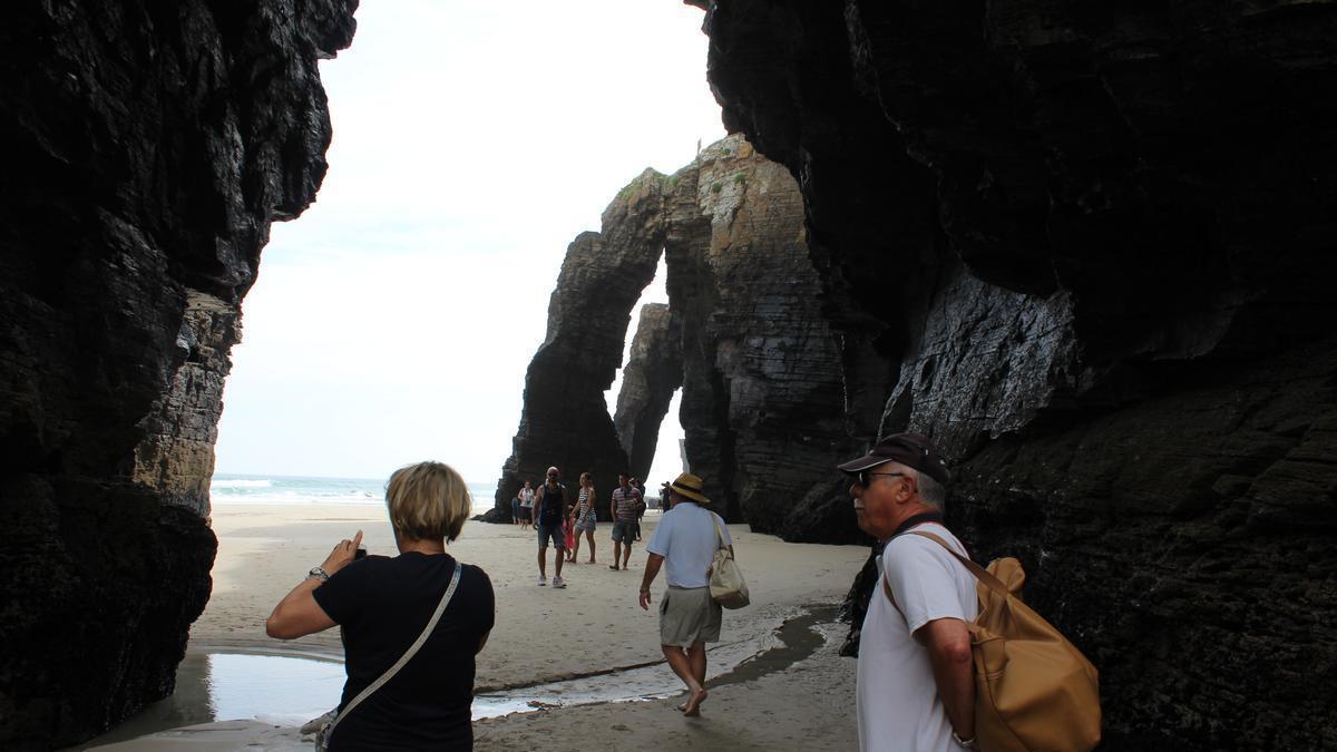 Turistas recorriendo la playa durante la bajamar.