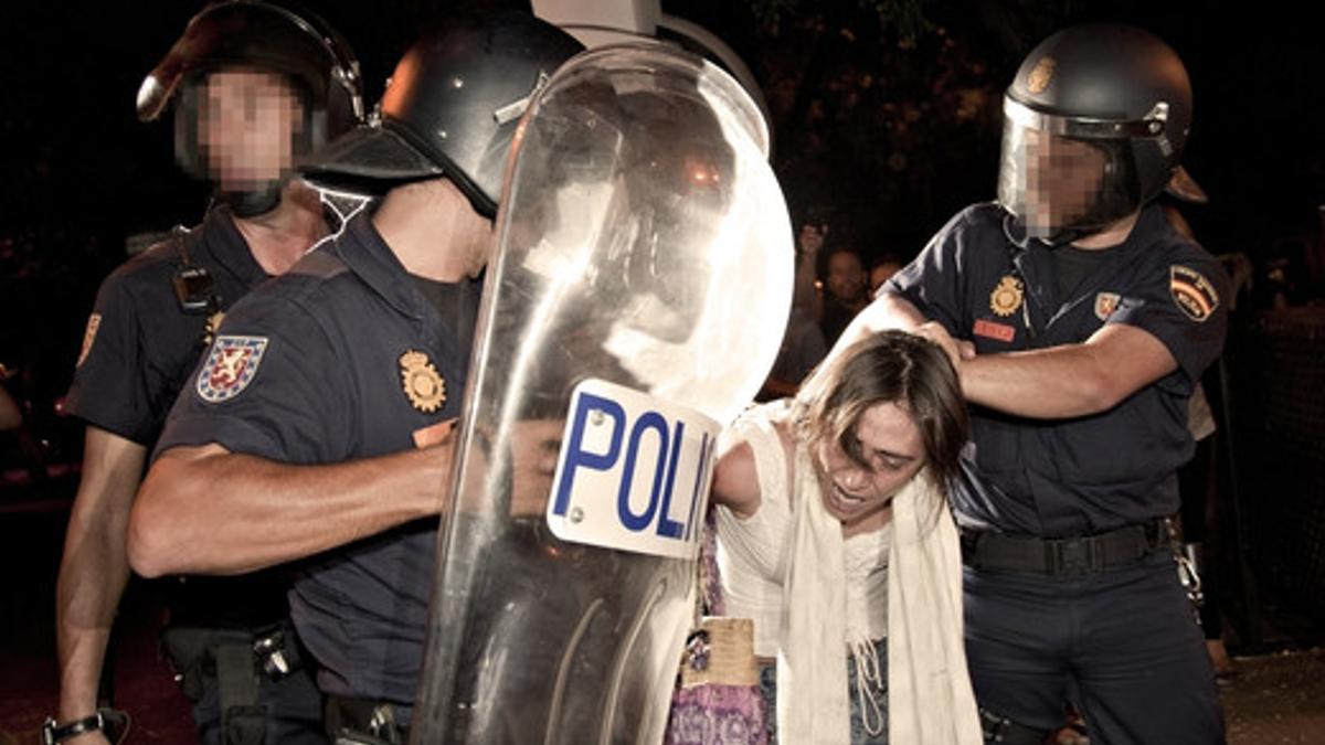 Miembros de la policia nacional retienen a una joven durante los incidentes.