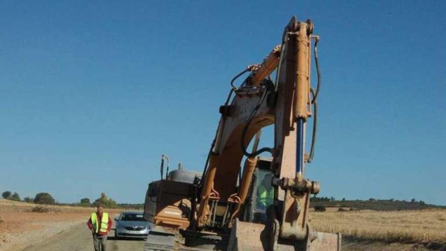 Una excavadora realiza trabajos en una carretera.