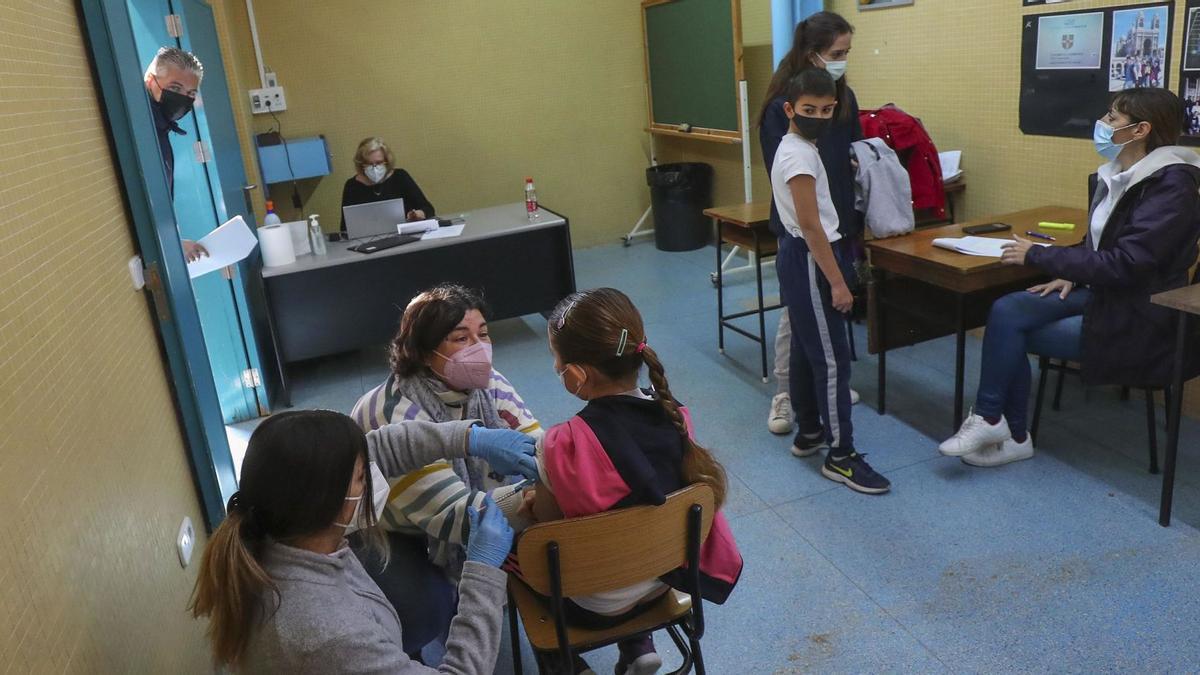 Una niña recibe la dosis
mientras otro escolar
es identificado en un 
colegio concertado de
València.  francisco calabuig | F.CALABUIG