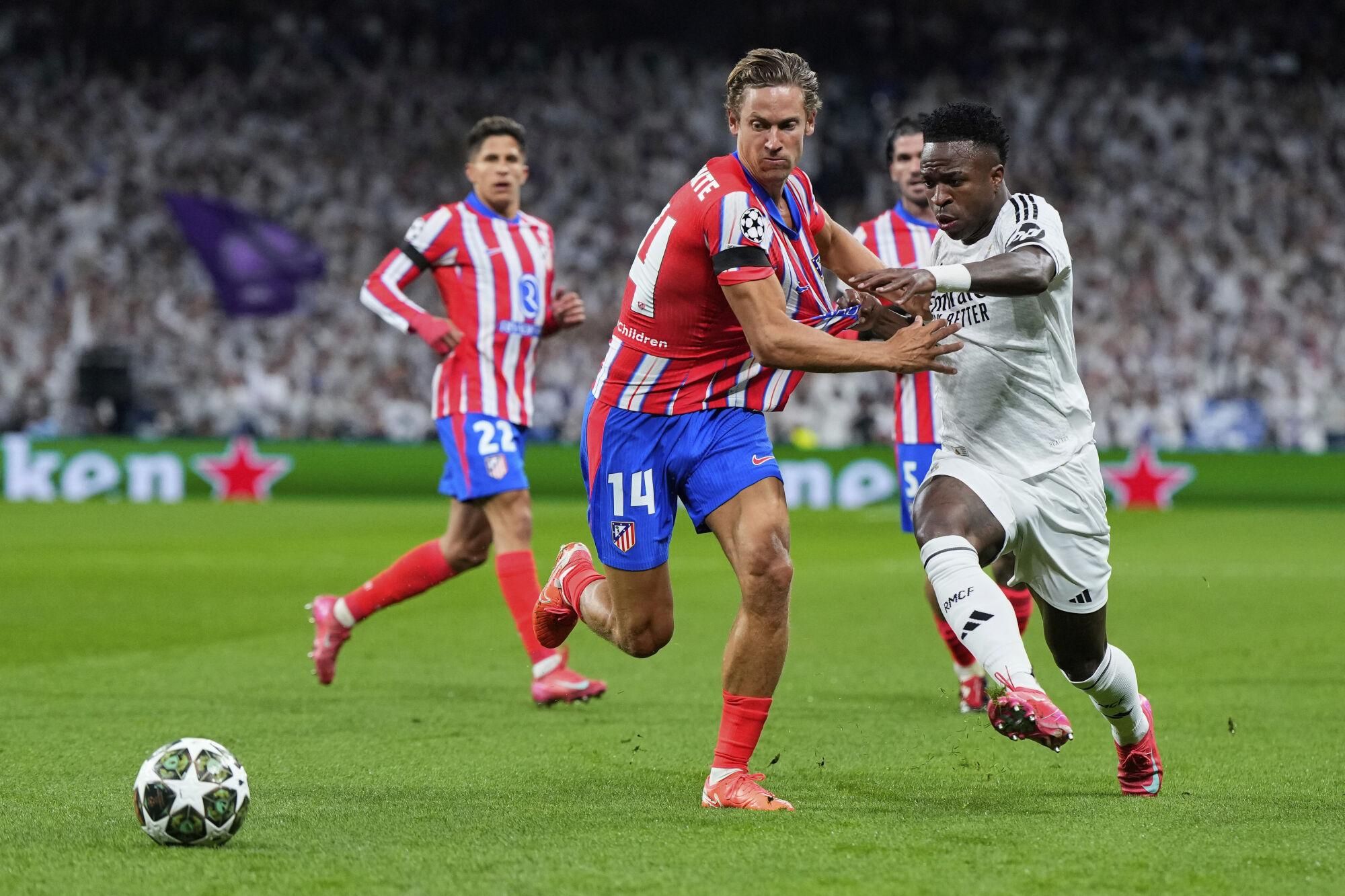 Atletico Madrid's Marcos Llorente, left, fights for the ball with Real Madrid's Vinicius Junior during the Champions League round of 16 first leg soccer match between Real Madrid and Atletico Madrid at the Bernebeu stadium in Madrid, Spain, Tuesday, March 4, 2025. (AP Photo/Manu Fernandez). EDITORIAL USE ONLY / ONLY ITALY AND SPAIN