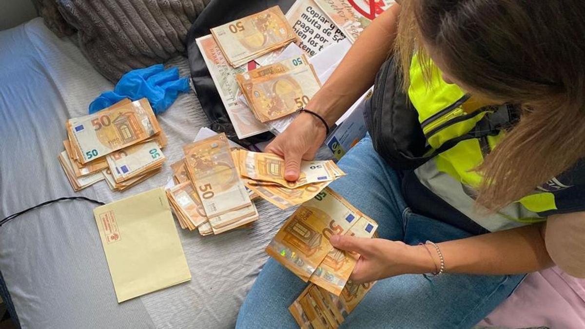 Una agente de la Policía Nacional cuenta dinero intervenido en la operación.