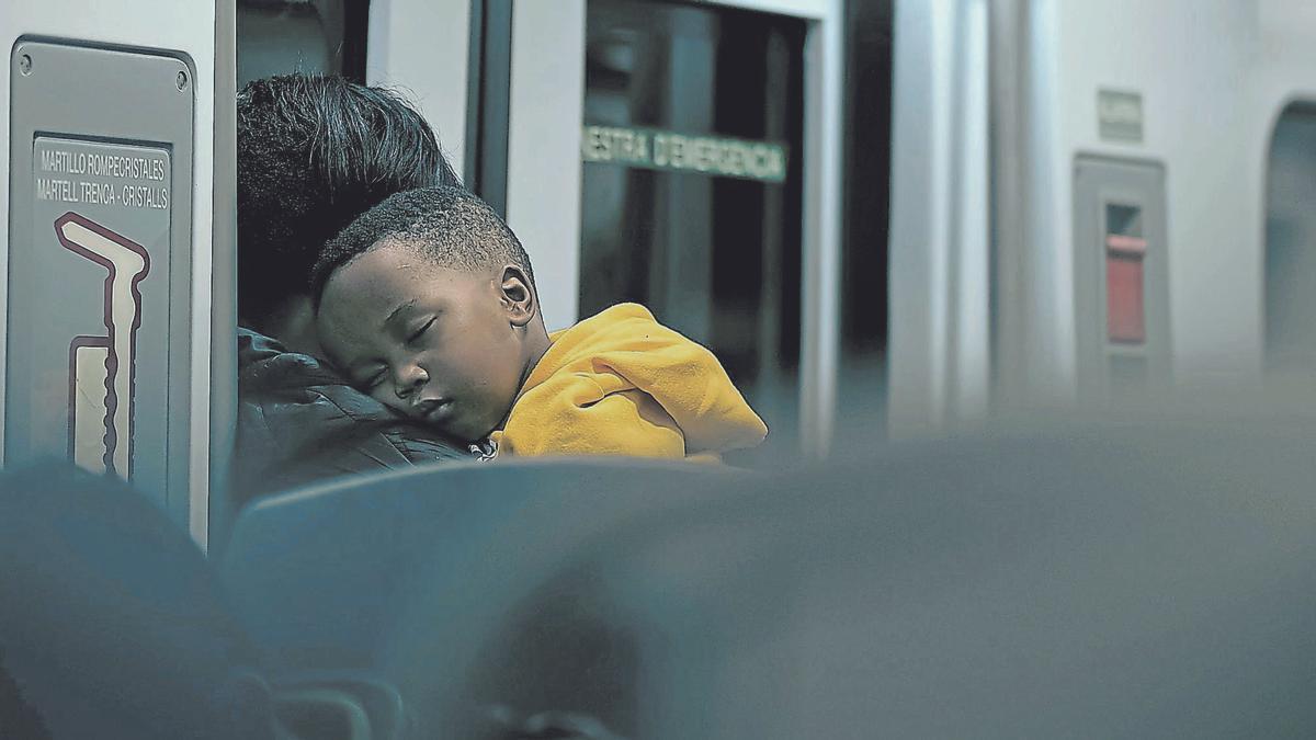 Un niño viaja dormido en brazos de su madre en el tren rumbo a Palma