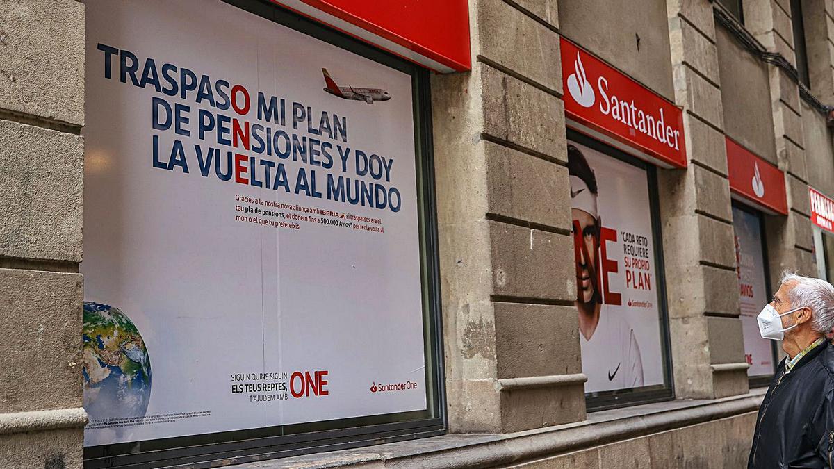 Un home llegeix cartells publicitaris de plans de pensions d’una entitat financera a Barcelona. | JORDI OTIX