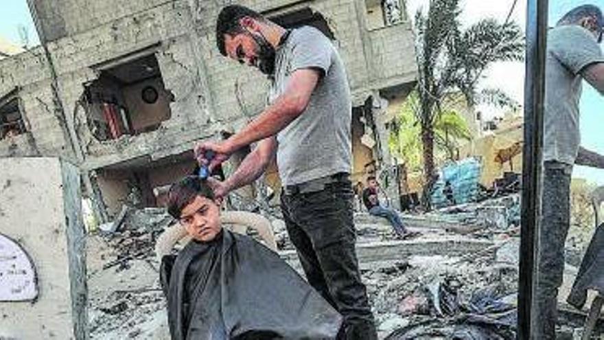 Un home talla els cabells a un nen al mig del carrer | EFE