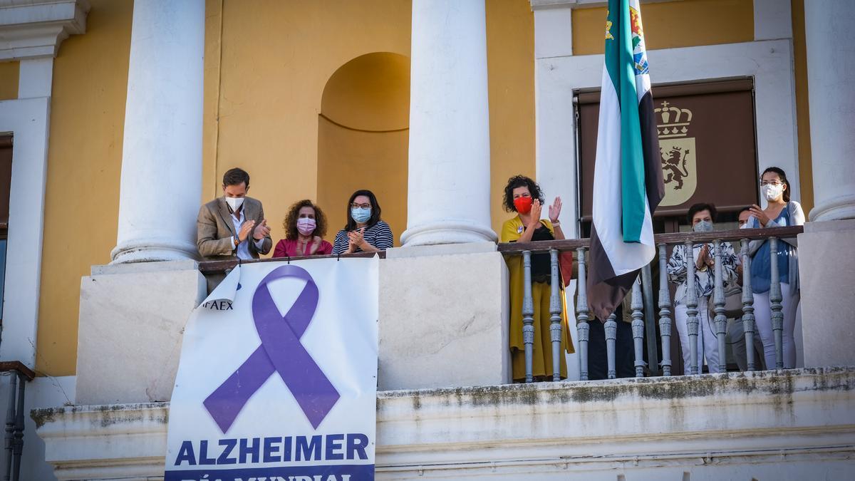 La presidenta de Afaex descuelga la pancarta en la fachada del ayuntamiento por el Día Mundial del Alzheimer junto a los concejales, ayer.