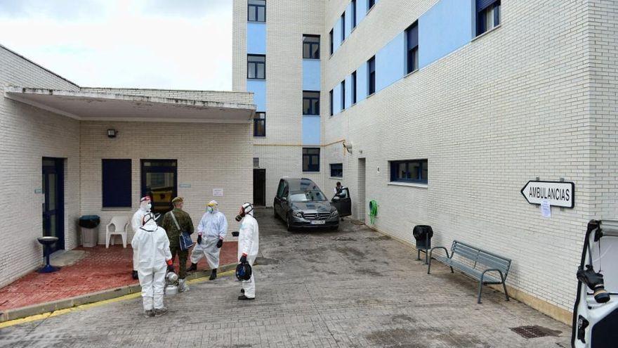 Imagen de archivo de preparativos para desinfectar la residencia Los Pinos, con un coche fúnebre al fondo.