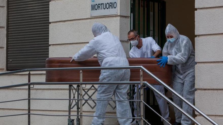 Tres operarios de una funeraria extraen a una persona fallecida del mortuorio del Hospital General de València este enero.  | F. BUSTAMANTE