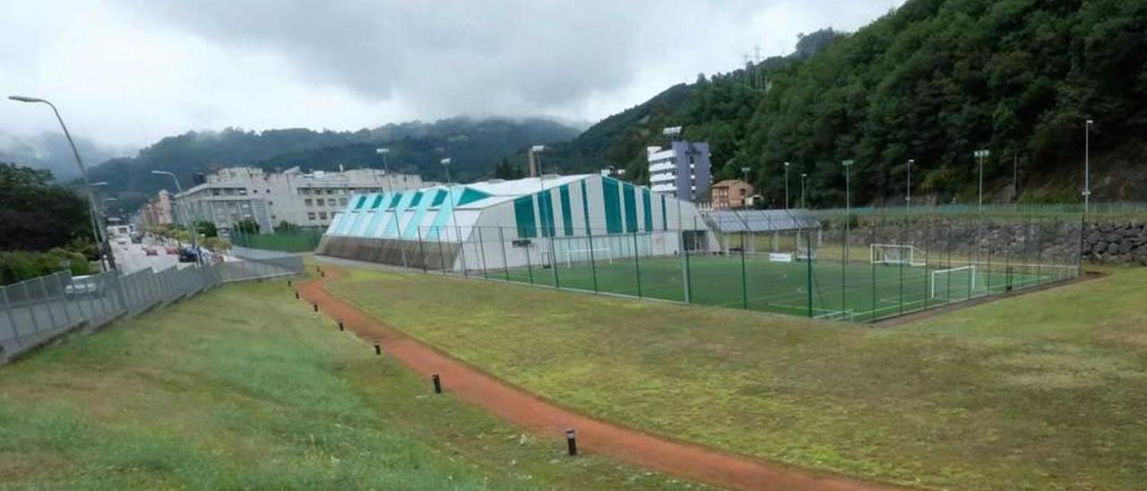 Las instalaciones deportivas del campus de Mieres, con las pistas de tenis en primer término, el pabellón y, al fondo, el edificio principal de Barredo.