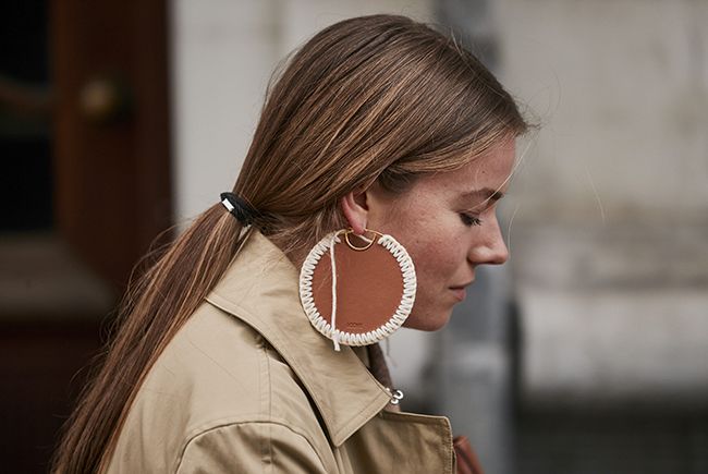 Street styler con coleta baja y pendientes XL en la semana de la moda de Copenhague