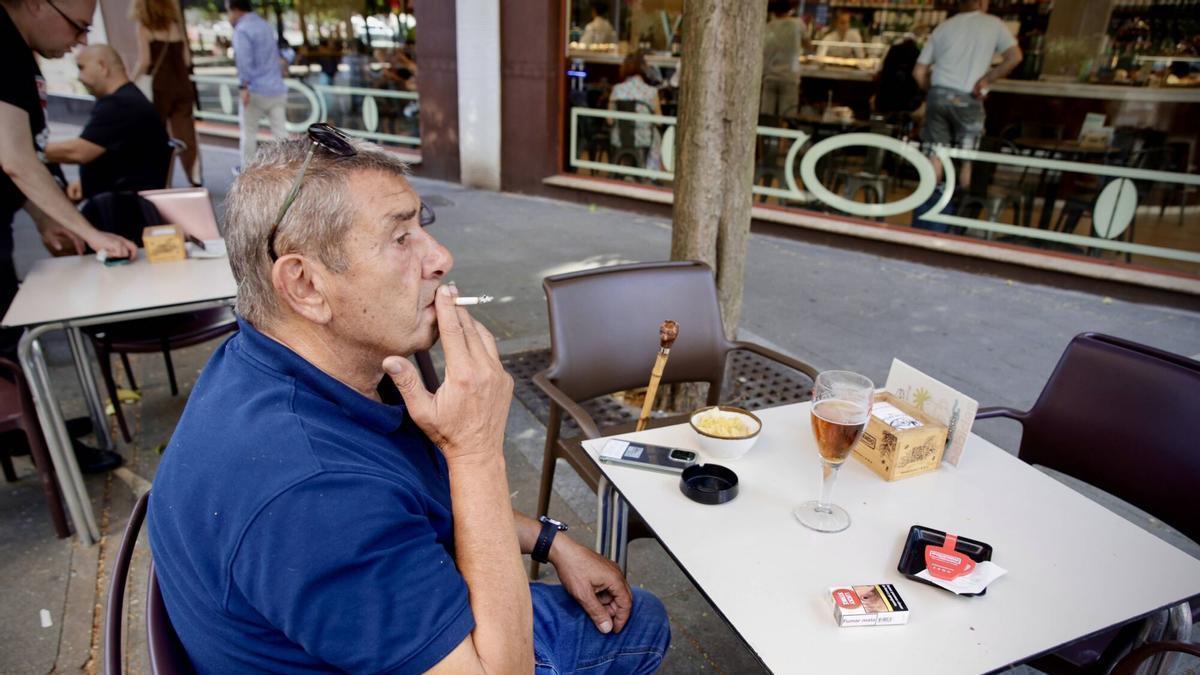Un cliente fuma en la terraza de "La Casa del Café", en el barrio gijonés del Humedal.