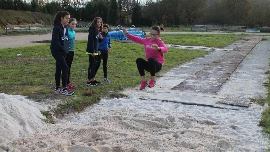 Selena Cabal realiza un salto de longitud ante la mirada de, por la izquierda, Aitana González, Carmen Fernández, María Río y David Sánchez, en una pista pendiente de mejoras.