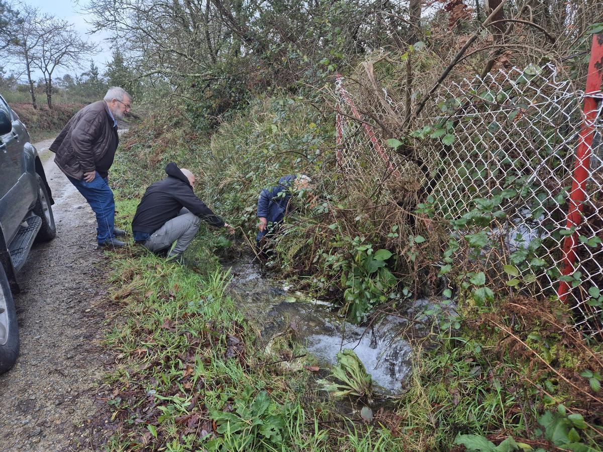 Concelleiros e un veciño de Razo avaliando o desaugadoiro da balsa de augas limpas.