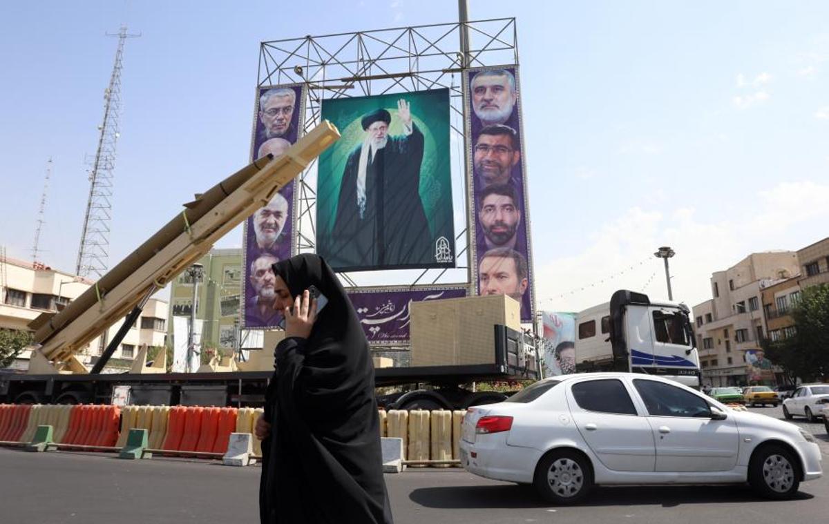 Una mujer pasa junto a un misil Kheibar desplegado en Teherán junto a un póster del ayatolá Ali Jamenei.