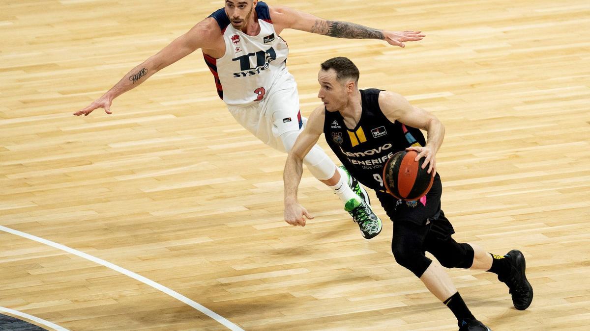 El base del Lenovo Tenerife, Marcelinho Huertas (d), avanza con el balón perseguido por el base del Baskonia, Luca Vildoza.