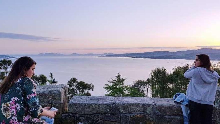 Dos mujeres contemplan la puesta de sol sobre la ría de Vigo, ayer en A Guía. // Marta G. Brea