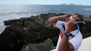 Un hombre prueba unas gafas especiales para mirar directamente al sol y poder ver el eclipse de hoy, en Mazatlan (México).