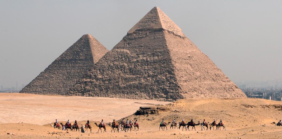 Turistas en su recorrido en camello ante las pirámides de Giza, en Egipto.
