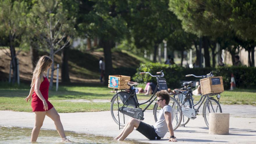 Dos jóvenes se refrescan como pueden en el viejo cauce del río Turia en València.