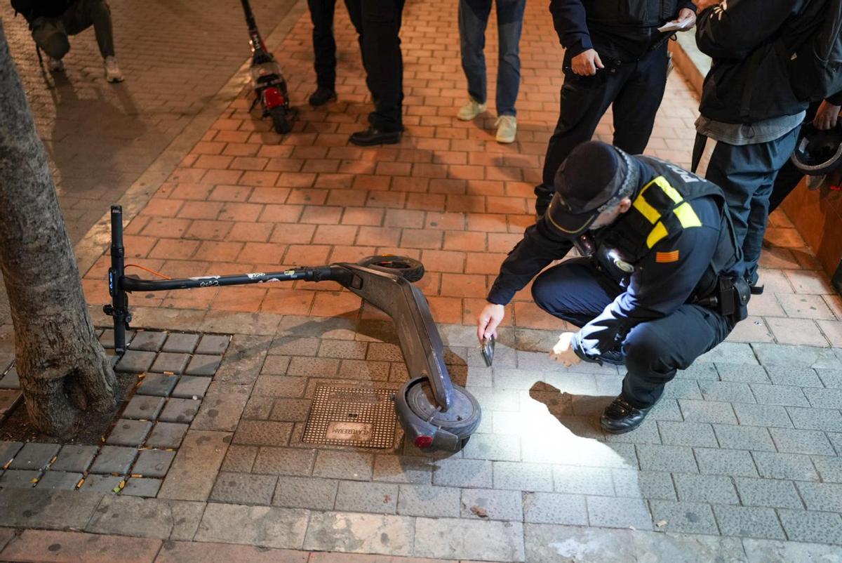 Un guardia urbano de Badalona revisa el número de serie de un patinete eléctrico, durante el dispositivo policial en el primer día de multas a VMP en la ciudad