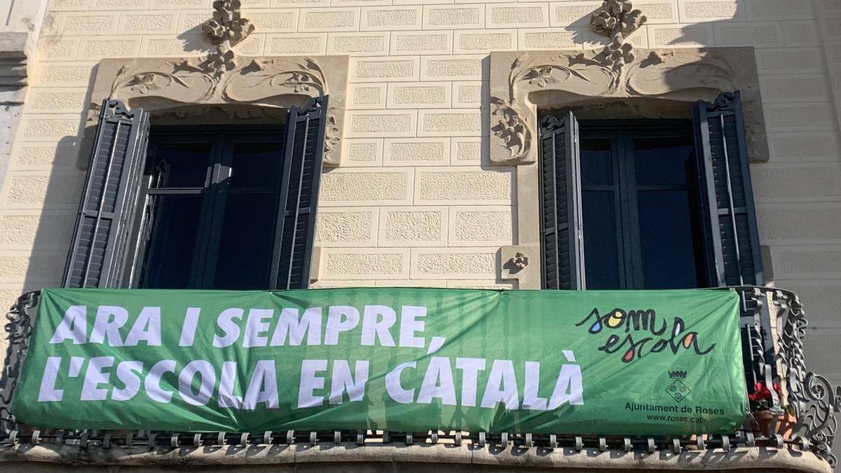 Pancarta penjada a la façana de l'Ajuntament de Roses durant un acte de suport a l’escola en català l'any 2022