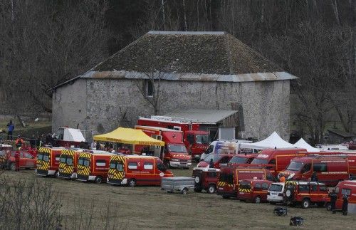 French fire brigade rescue units gather in a field near a building as they prepare to reach the crash site of an Airbus A320