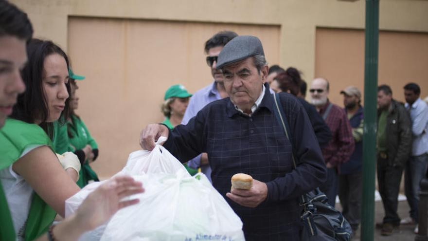 Un hombre coge una bolsa de comida en un banco de alimentos.