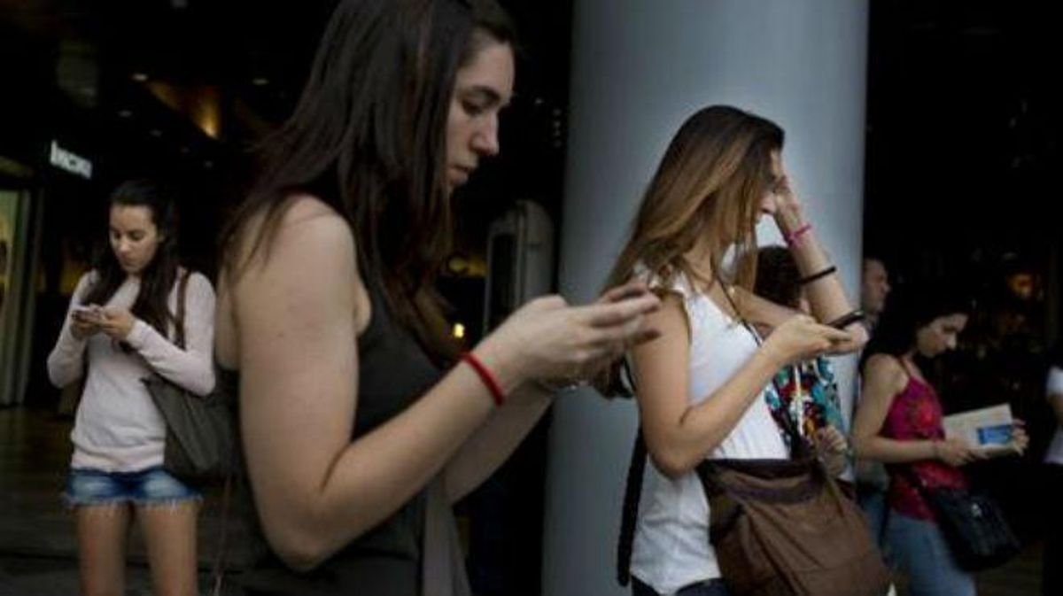 Joves utilitzen dispositius mòbils per comunicar-se o entretenir-se.