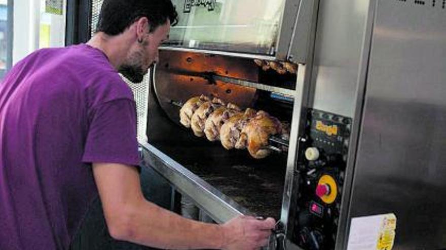 A la izquierda, un hombre se asoma para comprobar la evolución de los pollos asados de su establecimiento; a la derecha, un cliente compra en una frutería. | Emilio 
Fraile