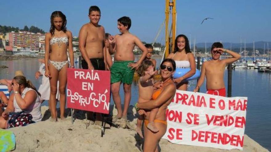 Bañistas en la playa con carteles en contra las obras del Náutico en el día de ayer.  // Santos Álvarez