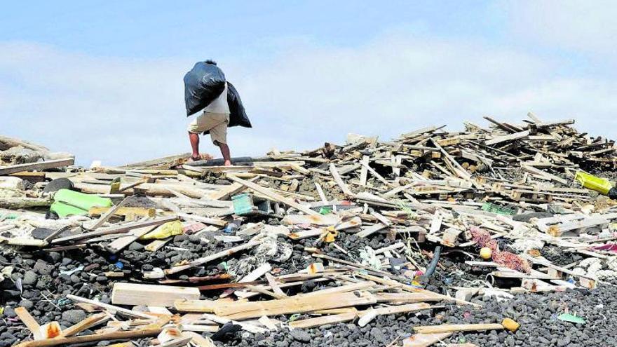 Un hombre porta dos bolsas con basura en Alegranza de un vertedero en la costa. | | ECOAQUA
