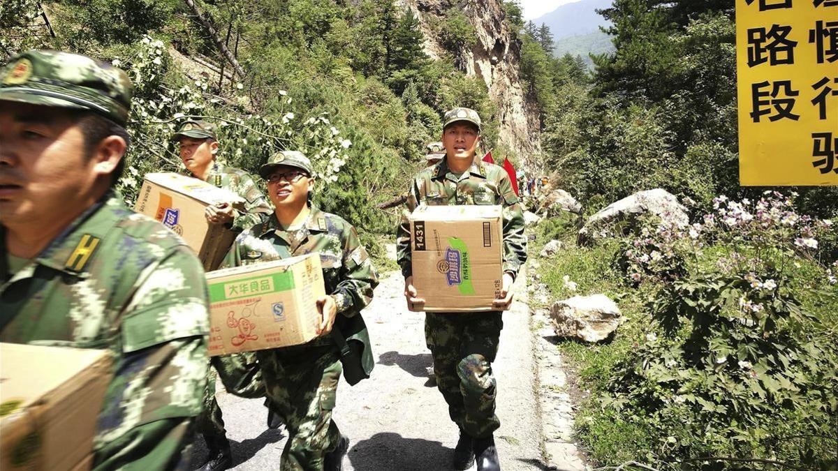 Policías paramilitares llevan cajas de ayuda humanitaria por una carretera destruida tras el terremoto en Jiuzhaigou (Sichuán), el 9 de agosto.