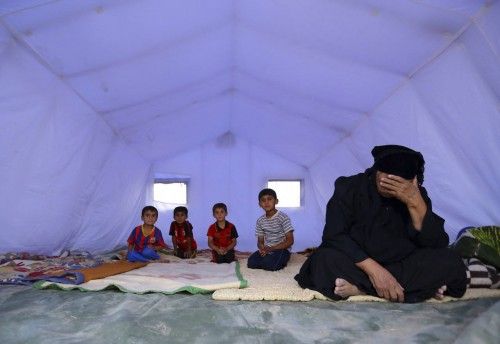 A family, who fled from the violence in Mosul, sits inside a tent at camp on the outskirts of Arbil
