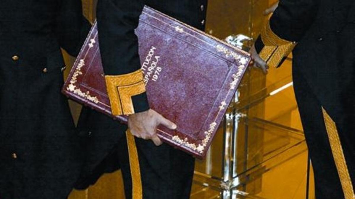 Un ujier del Senado traslada un ejemplar de la Constitución española.