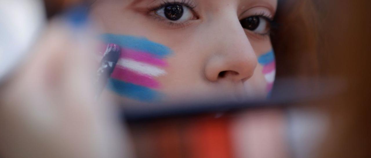 Una joven, con la  bandera trans pintada en la cara. | EFE