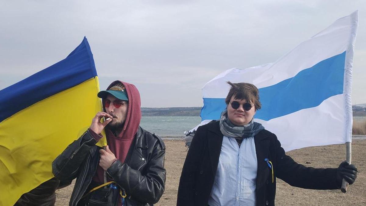 Nikita y otro manifestante ondena las banderas de Ucrania y la que utiliza la oposición rusa en un acto en el que quemaron un muñeco de Putin.