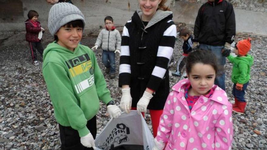 Nicolás García, Sara García y Eva Álvarez muestran una bolsa llena de restos de neumáticos.  | mónica g. salas