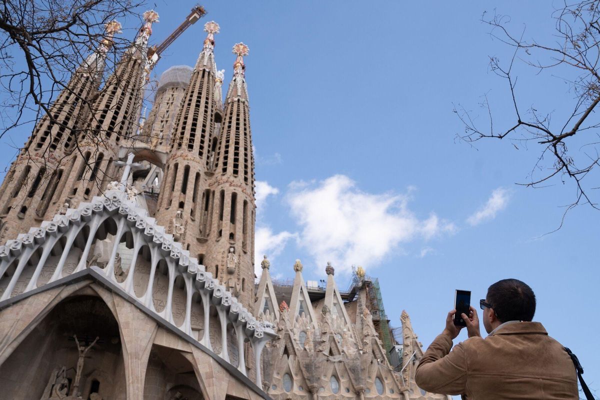 Un turista saca una foto junto a la Sagrada Familia, en 2024