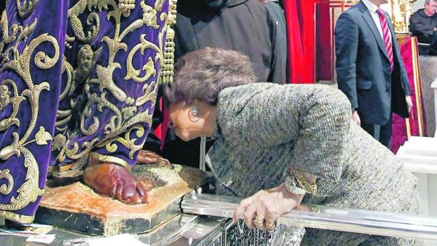 Doña Sofía se inclina para besar los pies del Cristo.