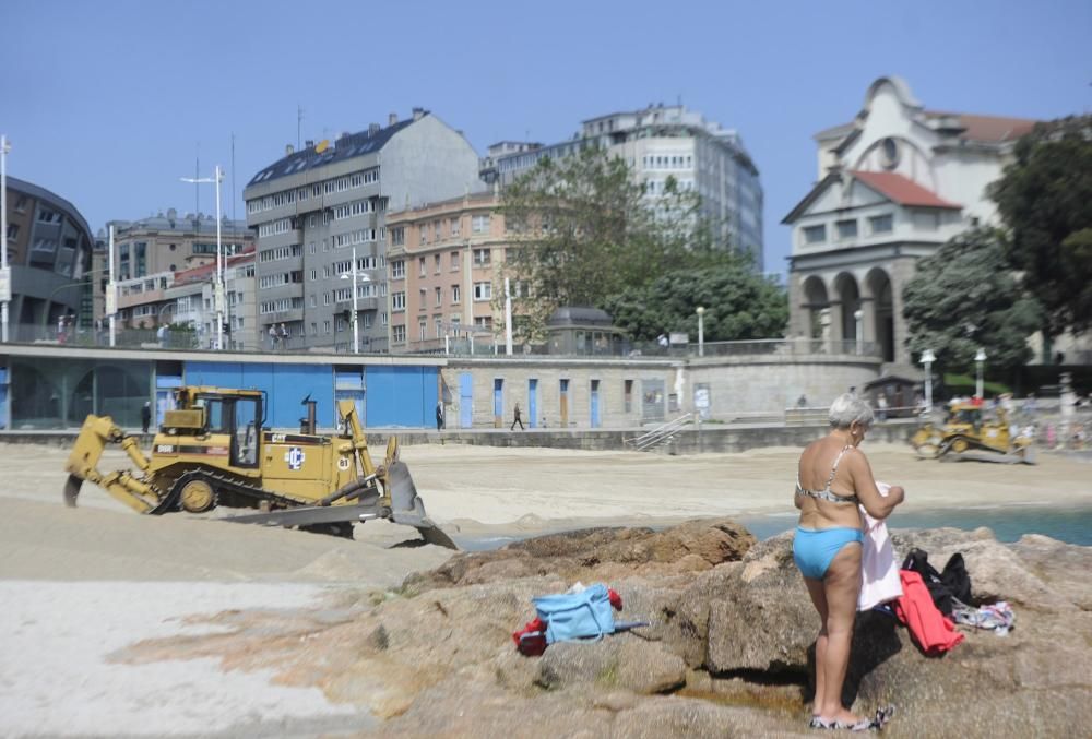 Las máquinas extienden la arena en la playa de Riazor.