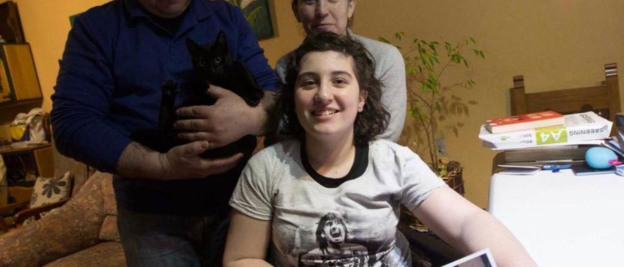 Clara González Vigil, con una camiseta y una foto de Melendi, y, tras ella, sus padres, Javier González Bueno, con la gata &quot;Nuca&quot;, y Elena Vigil Machargo. miki lópez