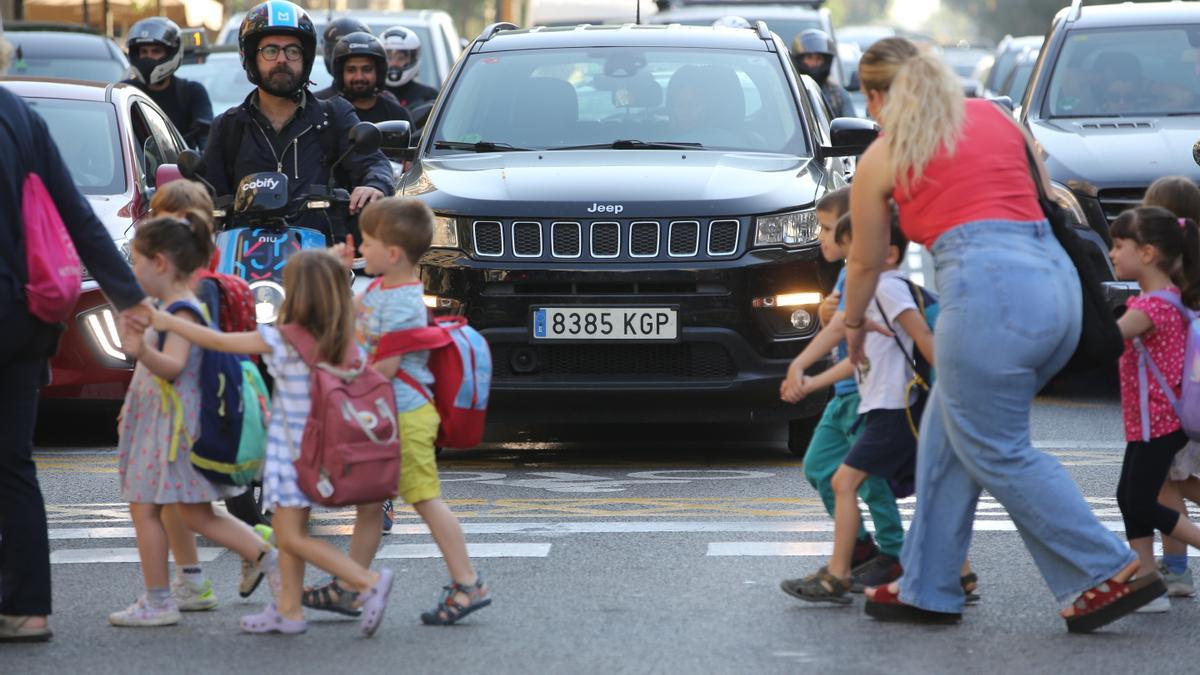 Un grupo de escolares cruza la calle de Aragó, en presencia de motos y coches