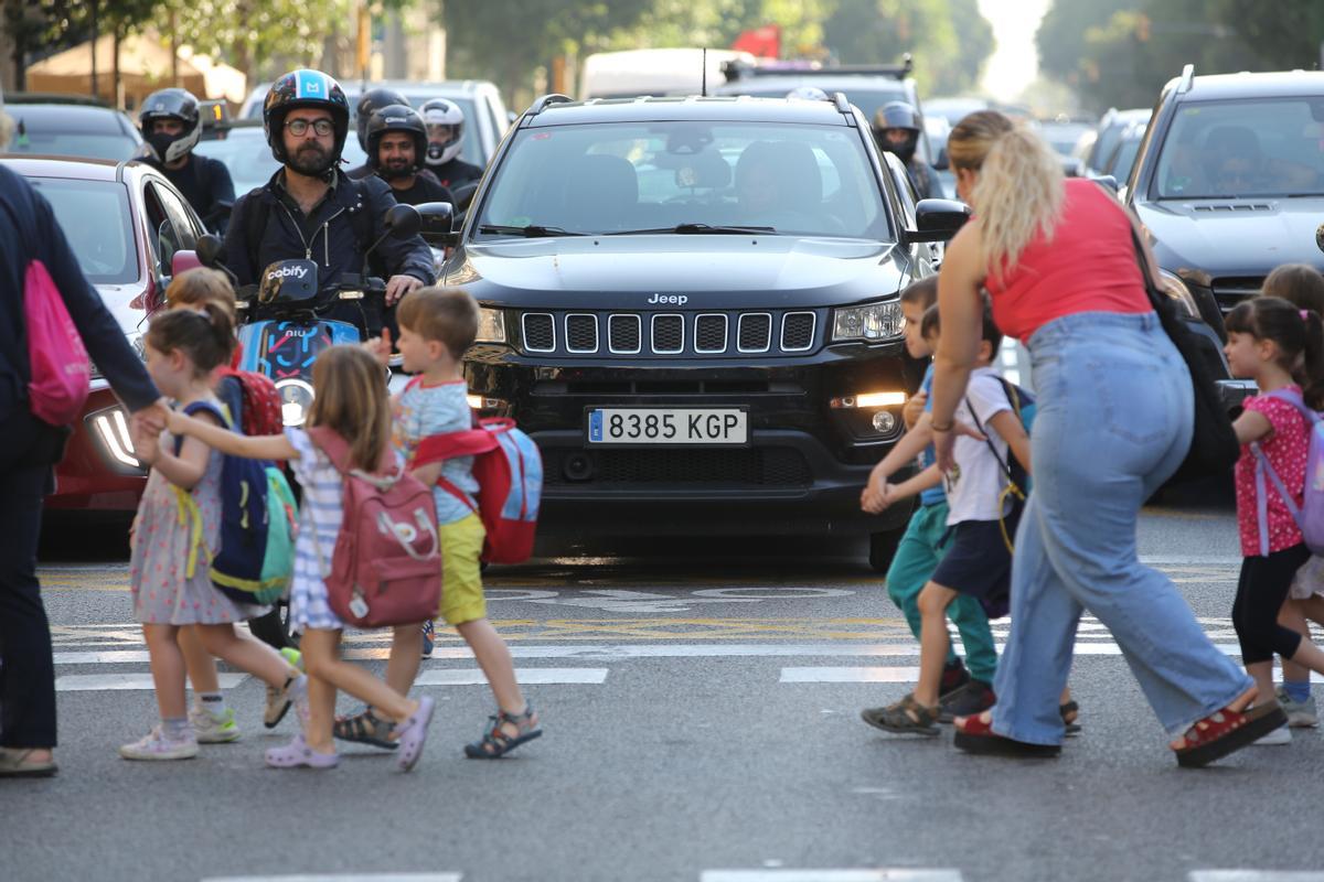 Un grupo de escolares cruza la calle de Aragó, en presencia de motos y coches